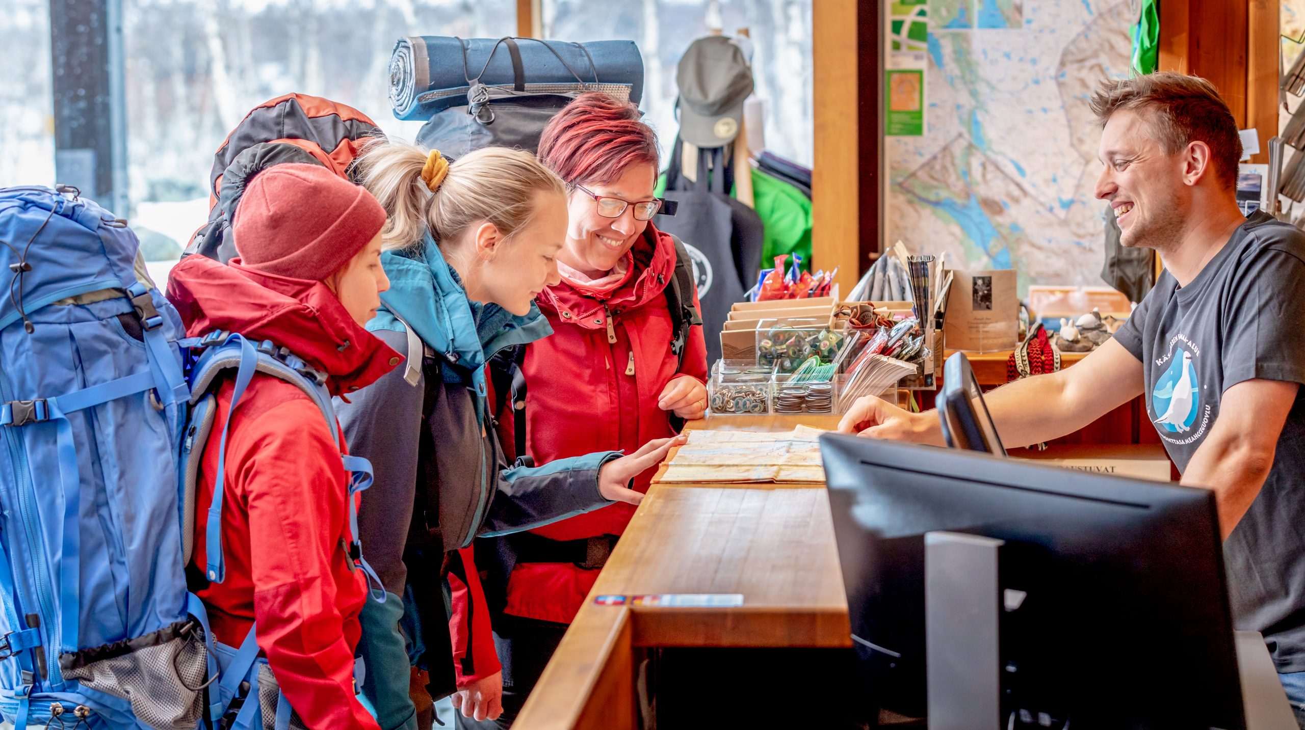 Staff member of the Kilpisjärvi Visitor Centre talking with hikers at the service desk