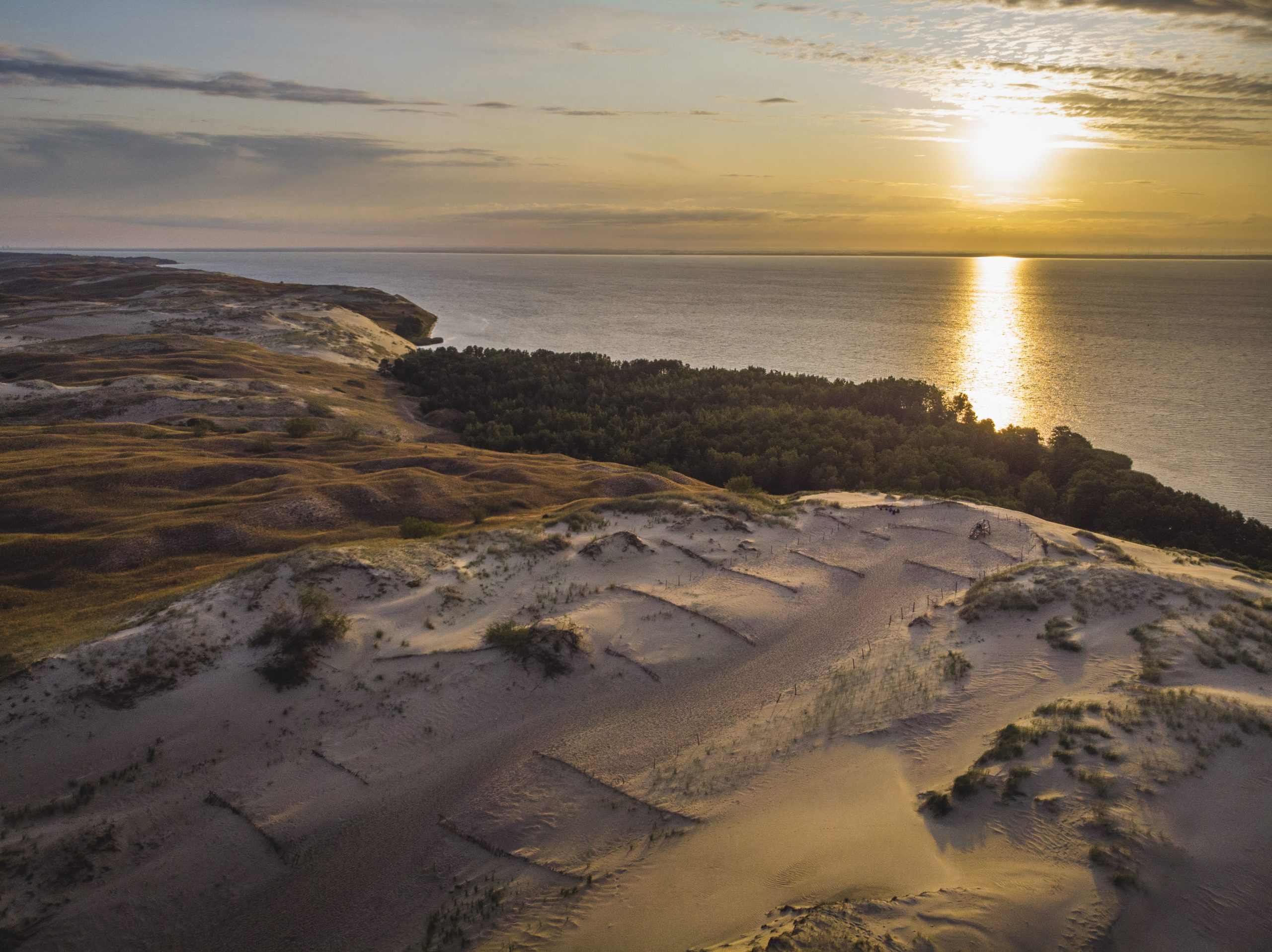 Sand dunes facing the sea with a sunset